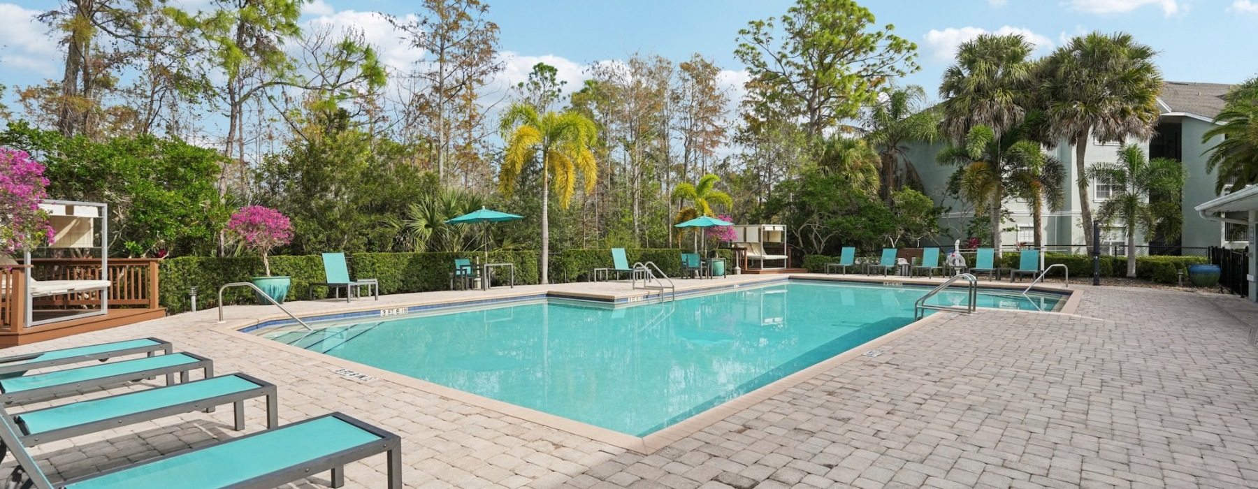 resort style pool with seating and a trees behind