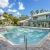 Dog-Friendly Apartments in North Naples, FL - Meadow Brook Preserve - Pool with Lounge Chairs, Umbrellas, and Palm Trees Surrounding It