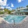 Dog-Friendly Apartments in North Naples, FL - Meadow Brook Preserve - Pool with Lounge Chairs, Umbrellas, and Palm Trees Surrounding It